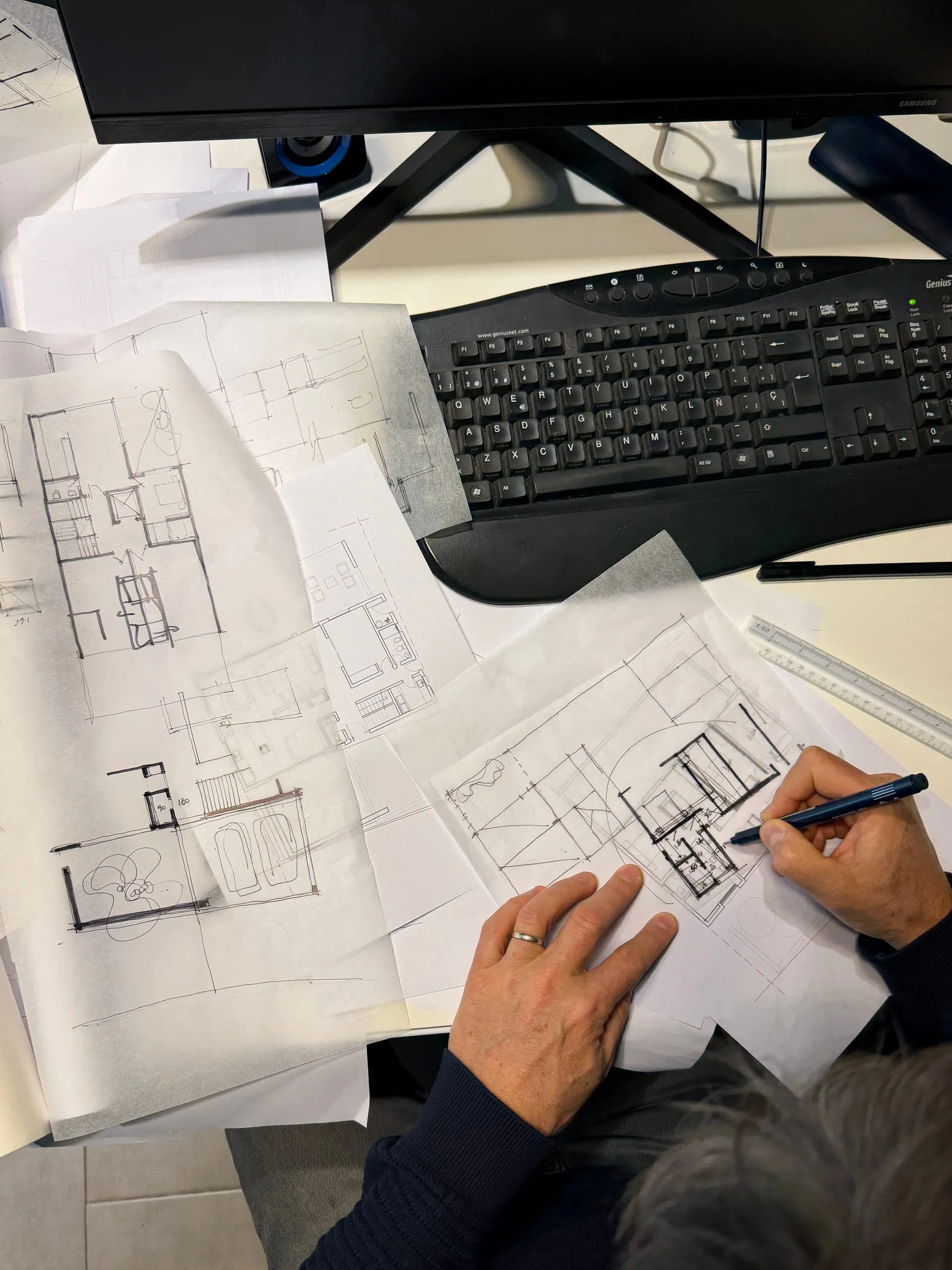 Uno de los arquitectos dibujando a mano sobre los planos, en el escritorio del estudio