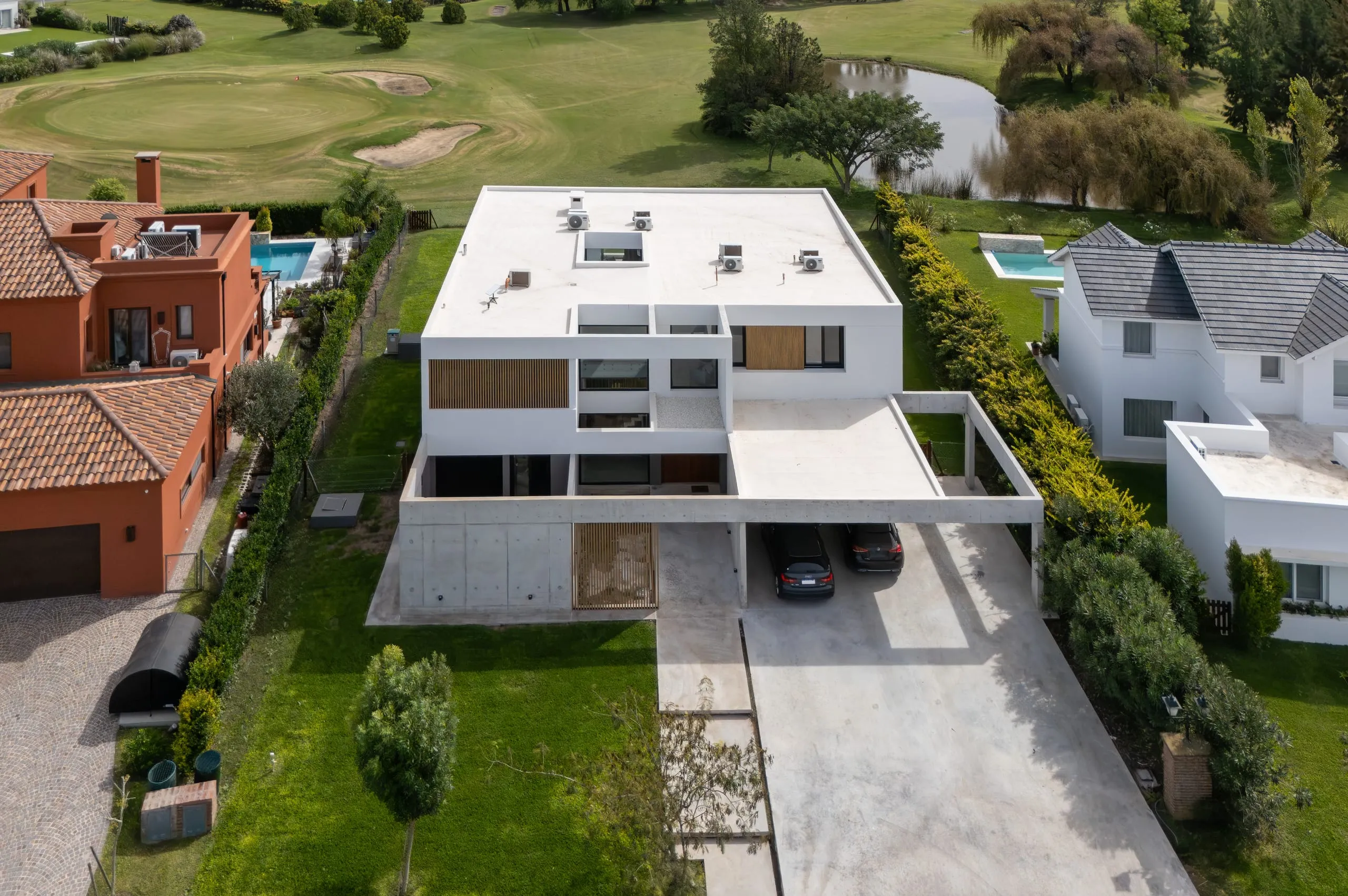 Vista aérea de la casa con la cochera y el jardín, entre casas vecinas