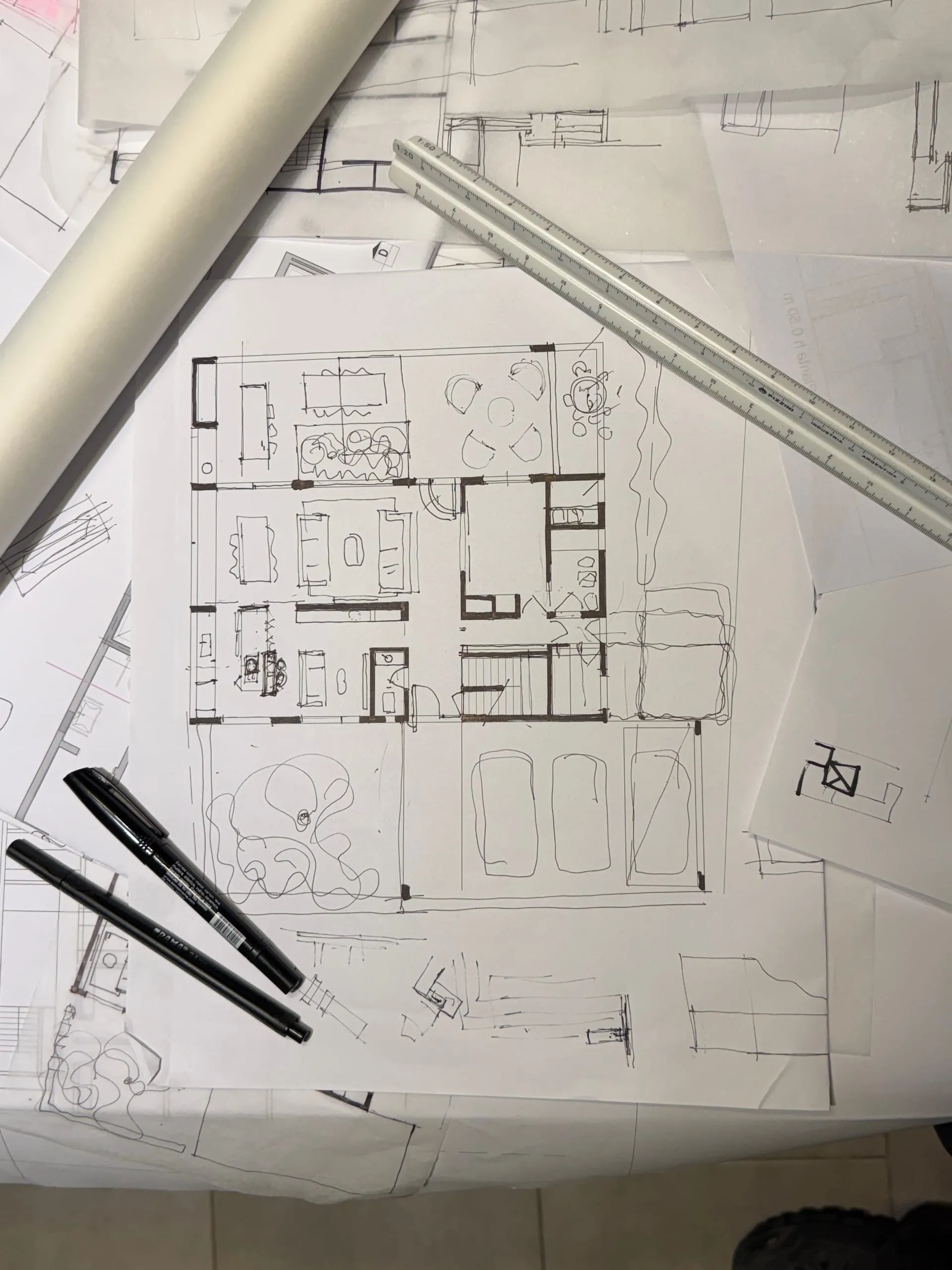 Plano de una casa dibujado a mano sobre la mesa de trabajo, con regla y marcadores