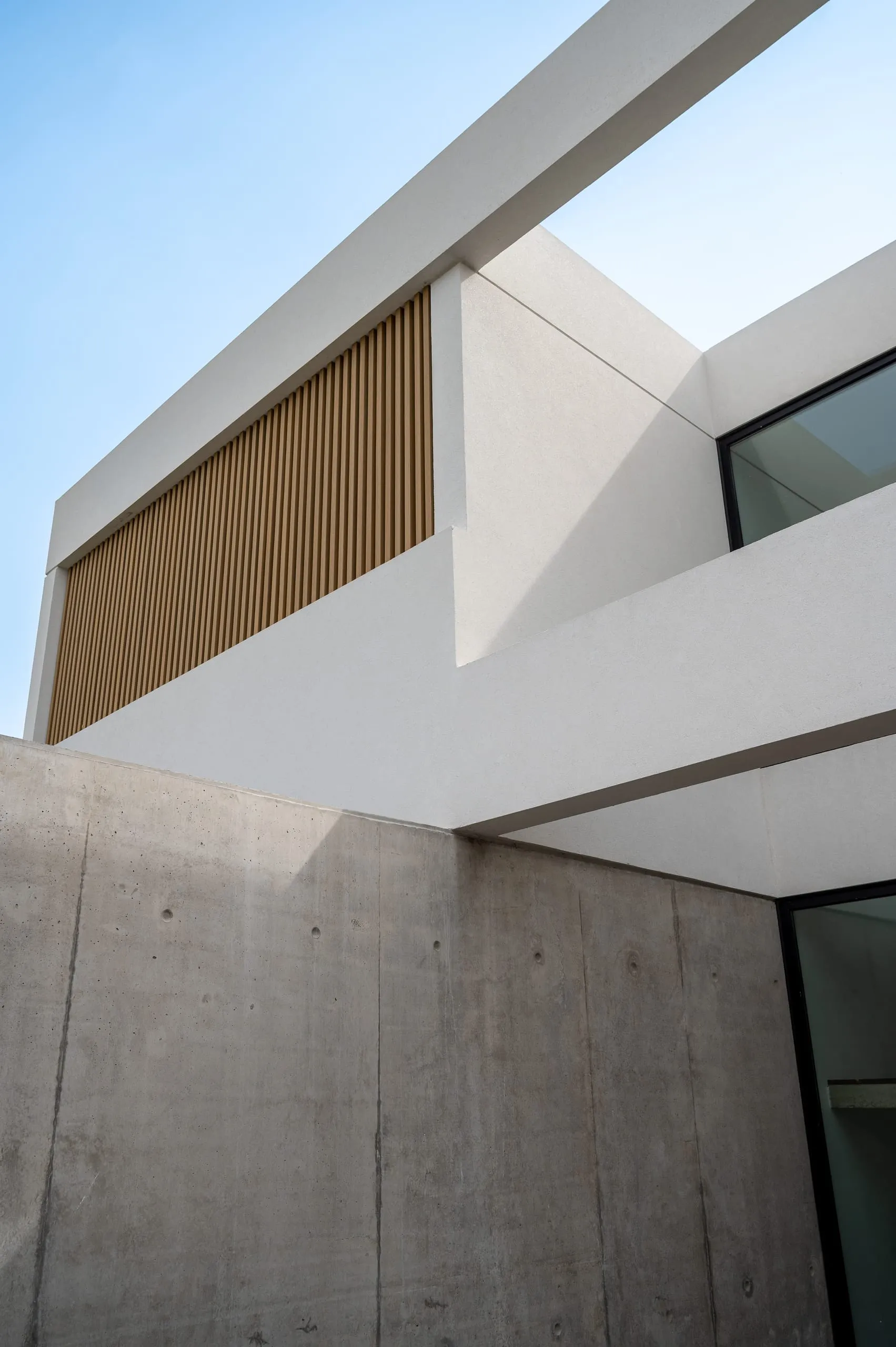 Detalle del volado blanco con listones de madera sobre el muro de hormigón