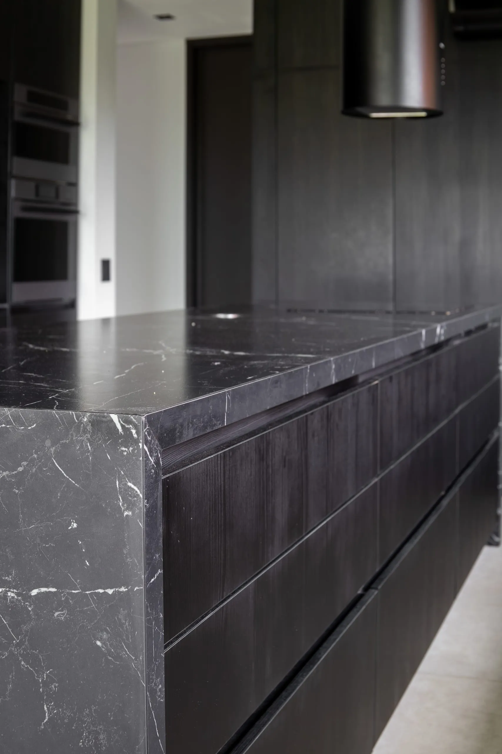 Detalle de la cocina con mesada de mármol negro y muebles oscuros