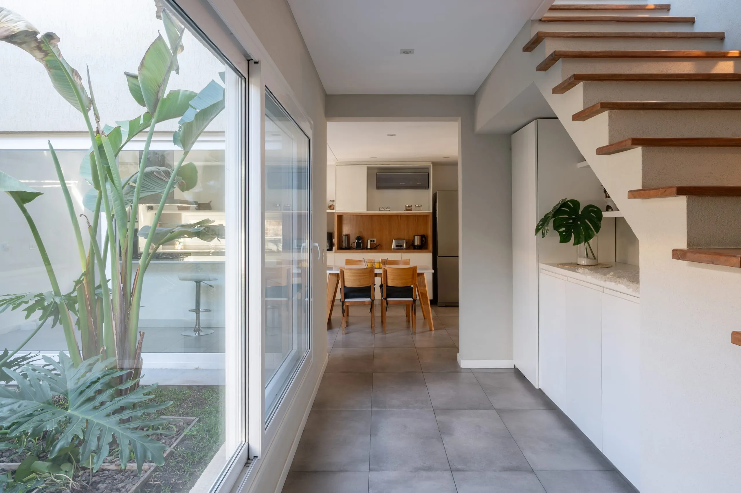 Pasillo de planta baja con escalera de madera y vista al comedor
