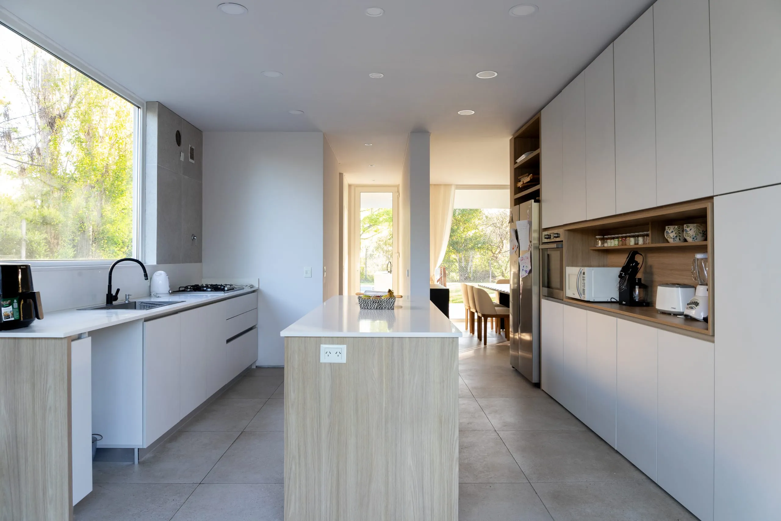 Cocina con isla revestida en madera y muebles blancos de piso a techo