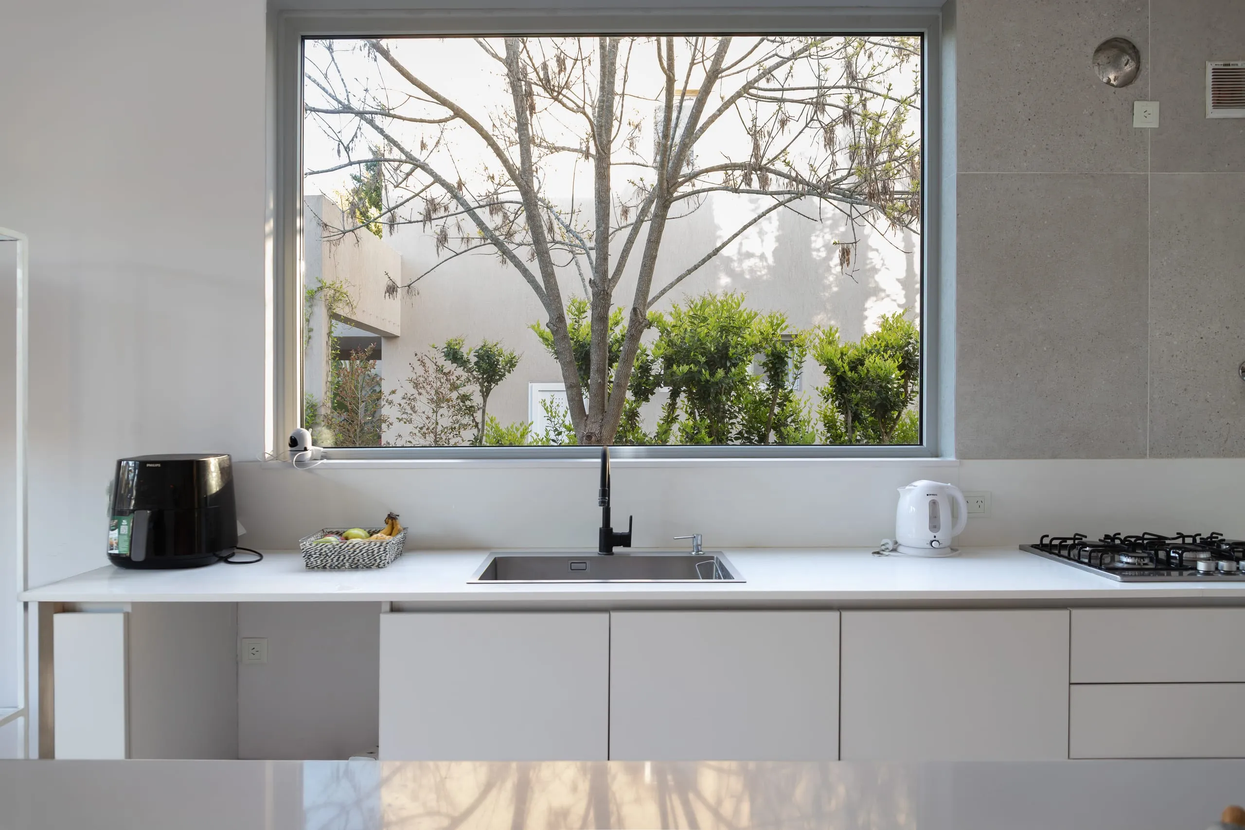 Mesada de la cocina bajo un ventanal con vista al jardín