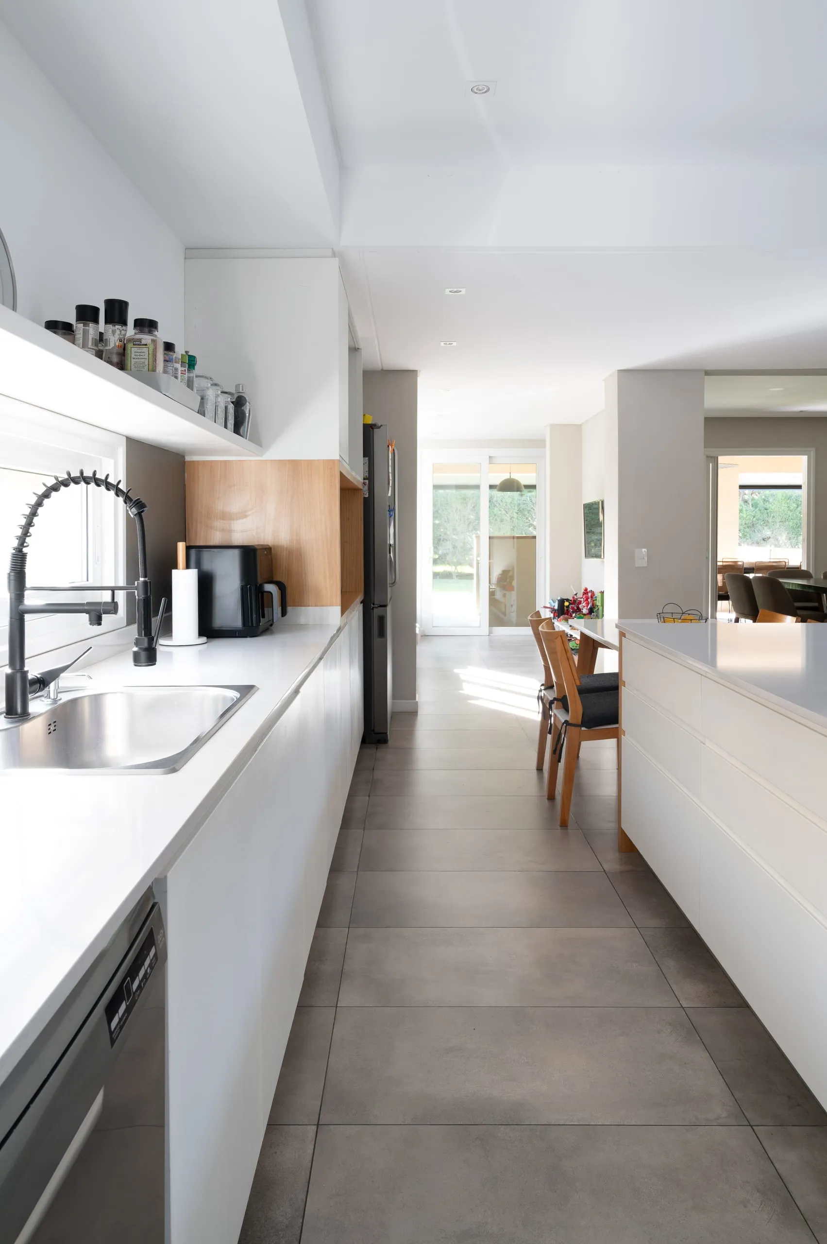 Cocina lineal con mesada blanca hacia el comedor