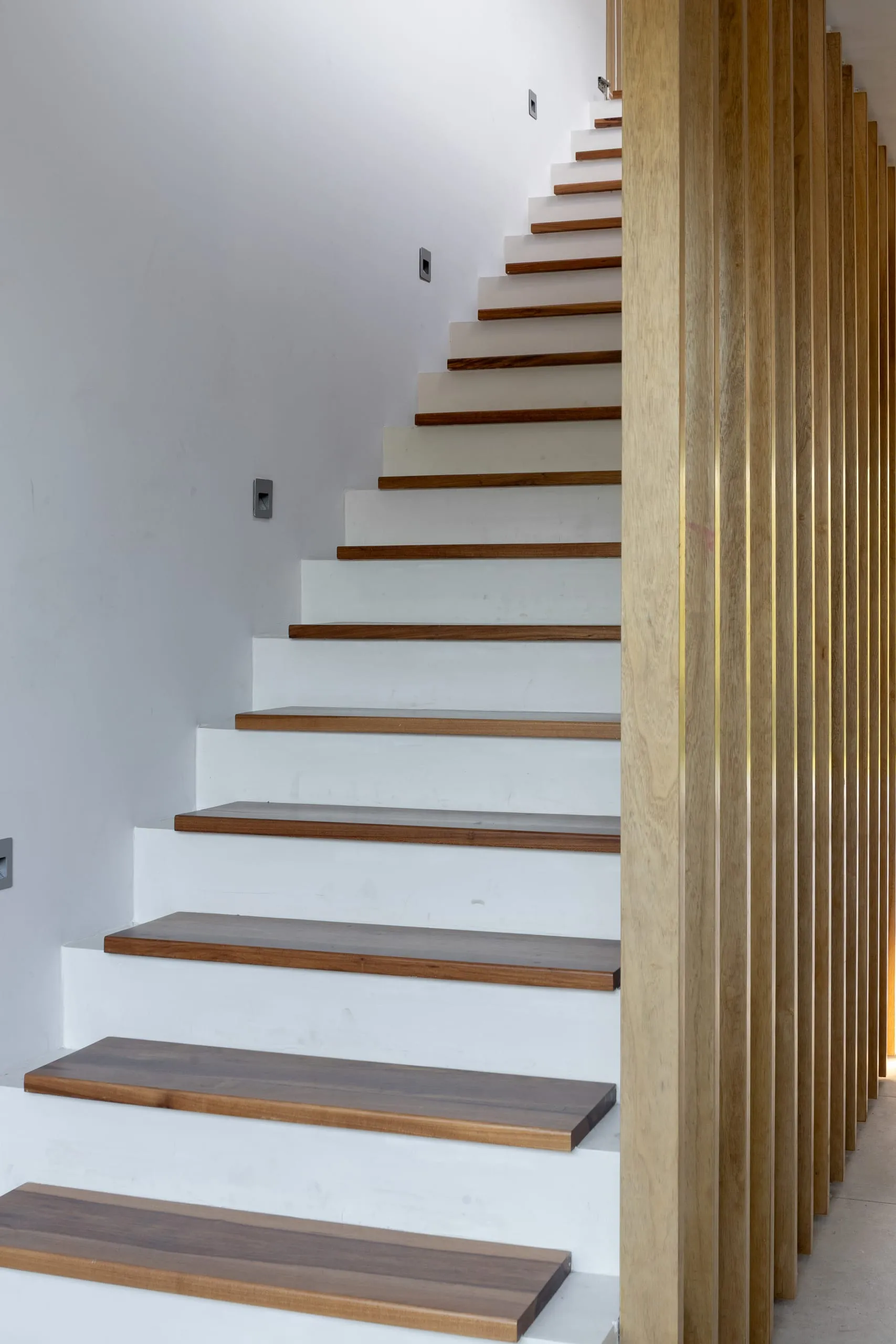 Escalera de peldaños de madera junto a un cerramiento de listones