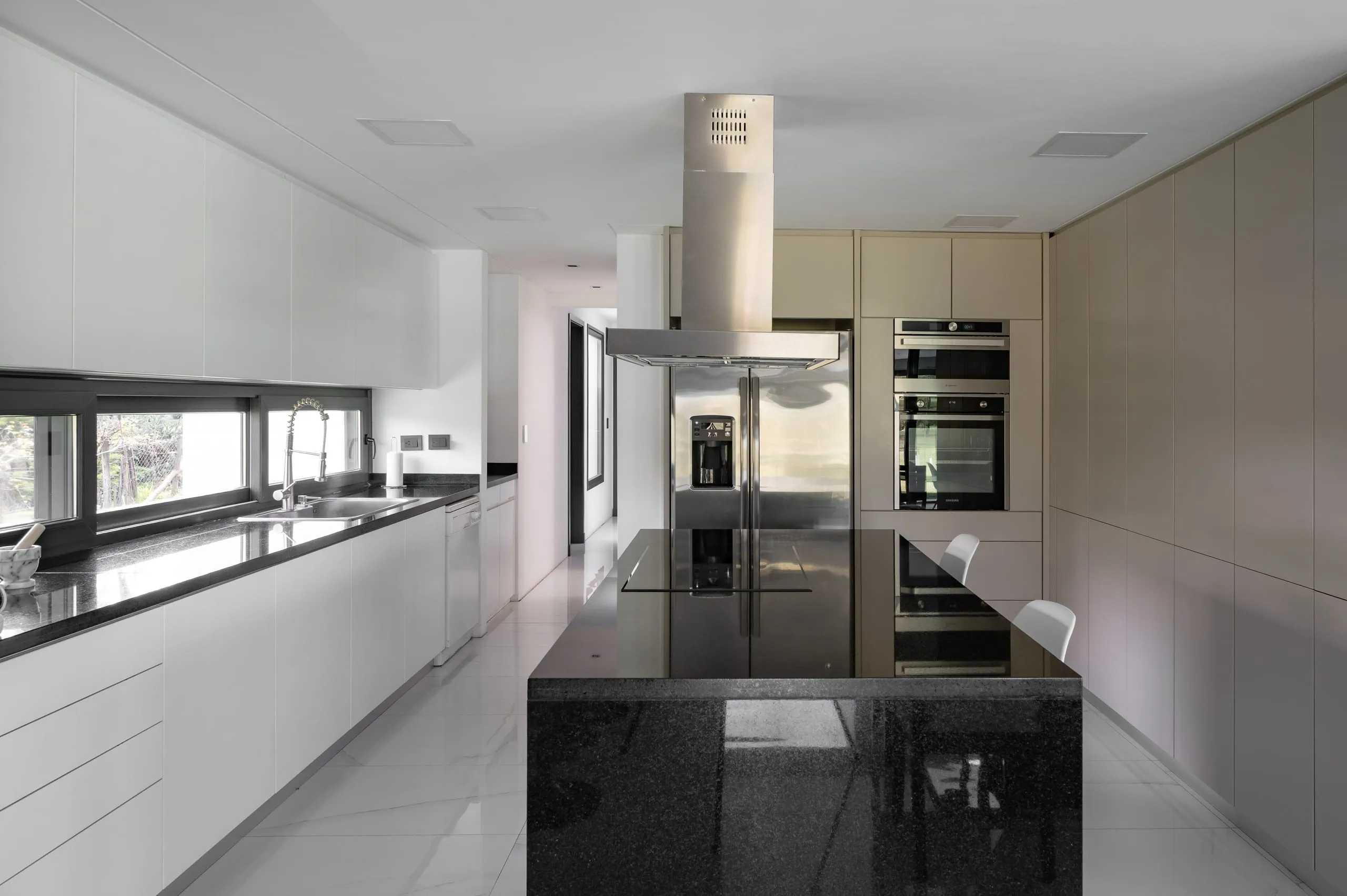 Cocina con isla de granito negro y muebles blancos