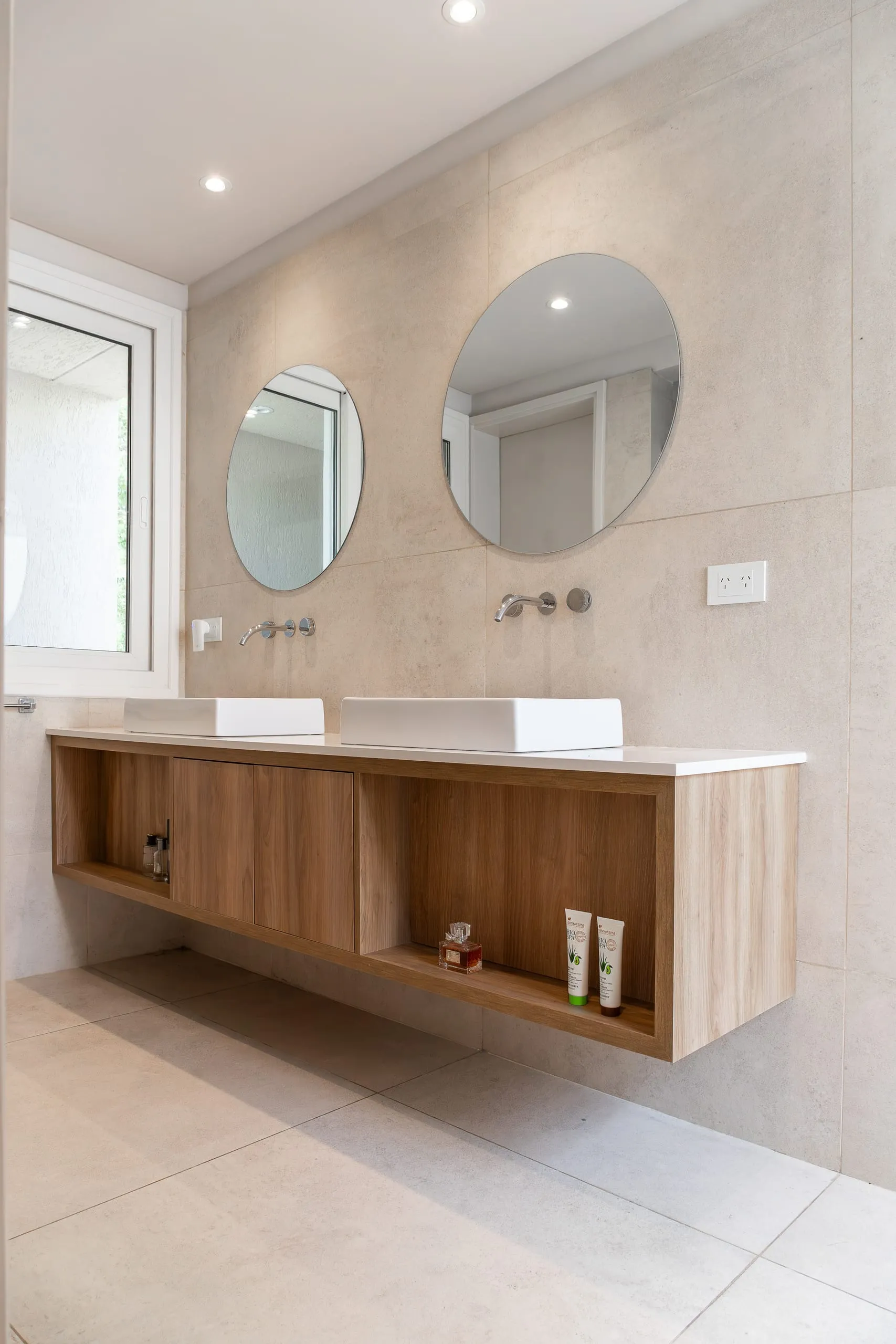 Baño con espejos redondos y vanitory de madera