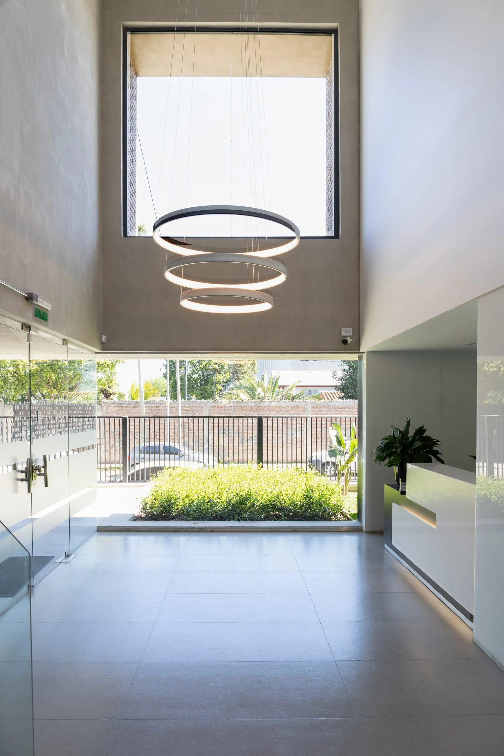 Hall de doble altura con lámpara de anillos y ventanal