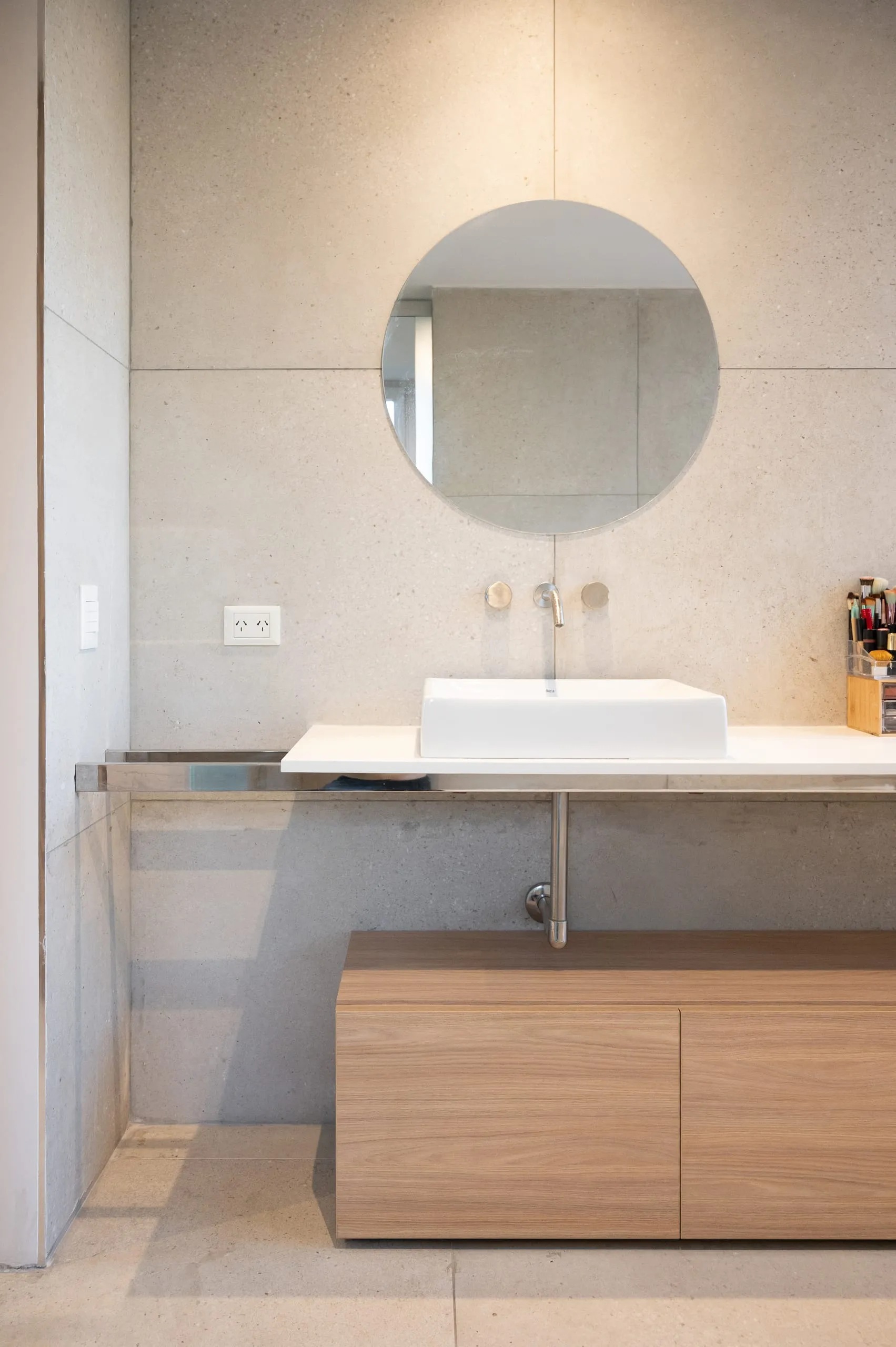 Baño con espejo redondo y vanitory de madera