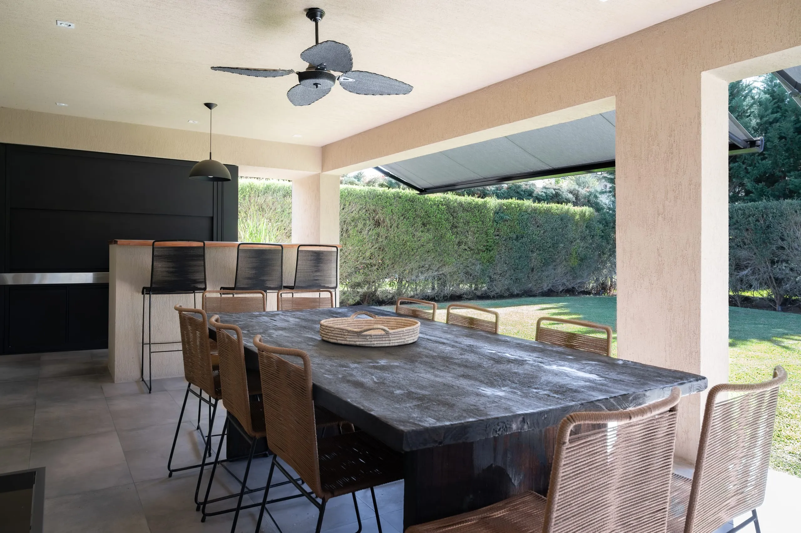 Quincho con mesa de piedra, banquetas y ventilador de techo