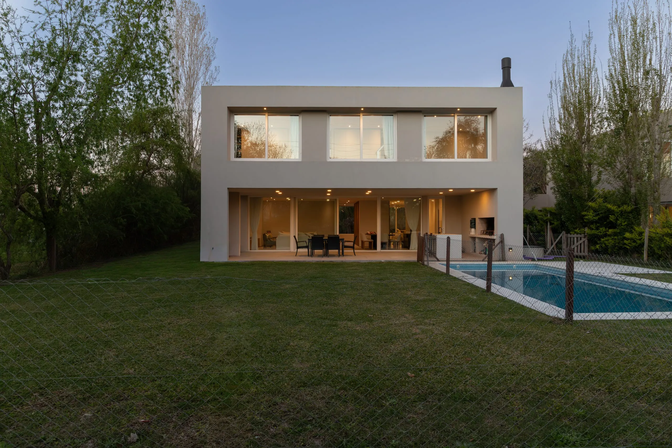 Contrafrente al atardecer, con la galería iluminada y la pileta