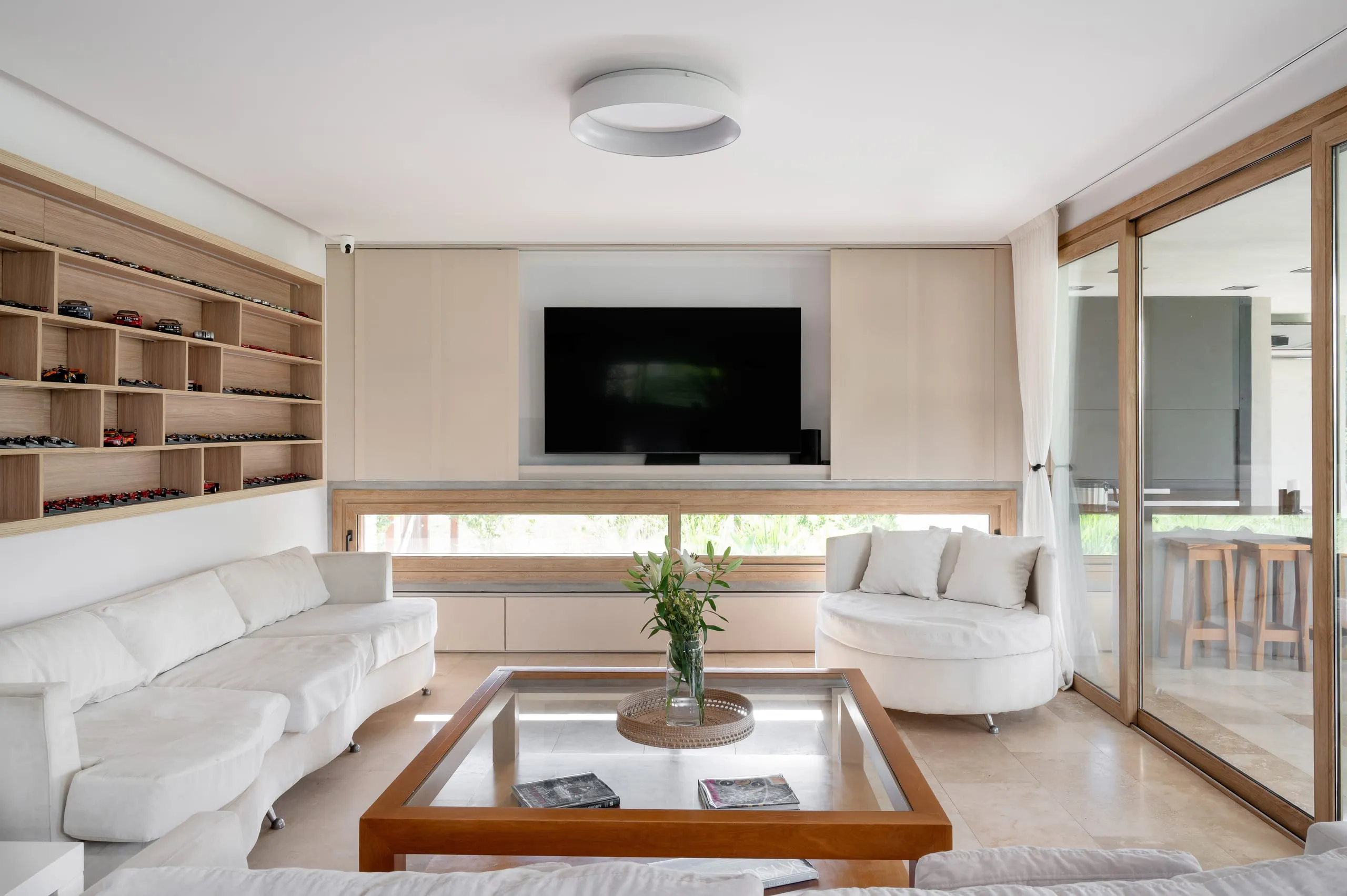 Estar con sillones blancos, biblioteca de madera y ventanal